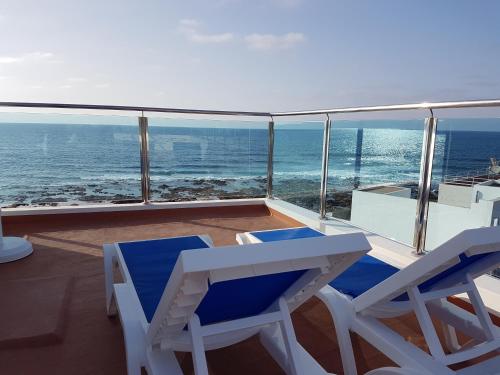 two chairs and a table on a balcony with the ocean at Casa Playa Ondina in Gáldar