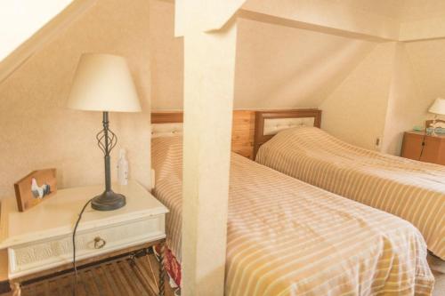 a bedroom with two beds and a lamp on a nightstand at Nikko Park Lodge Mountain Side in Nikko