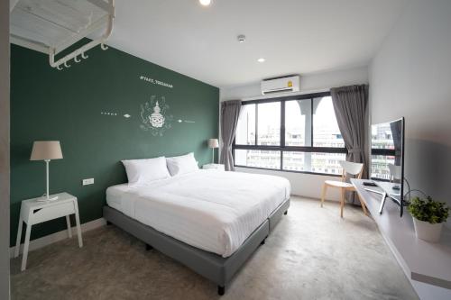 1 dormitorio con cama y pared verde en Yaks House Hostel - SHA Plus, en Bangkok