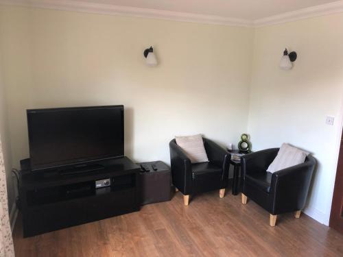 a living room with two chairs and a flat screen tv at Mountfield in Freshwater