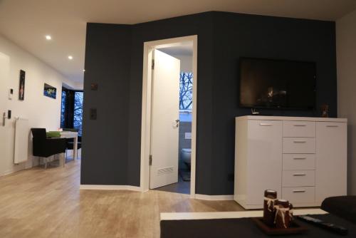 a living room with a television and a white cabinet at Wohnkomfort wie Zuhause in Neubrandenburg