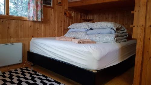 een bed in een houten kamer met handdoeken erop bij Cozy Cabin in the Woods in Selfoss