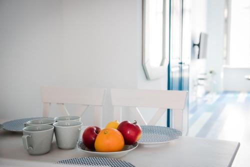 a table with bowls of apples and oranges on it at Pause Apartment with Free Parking in Budapest