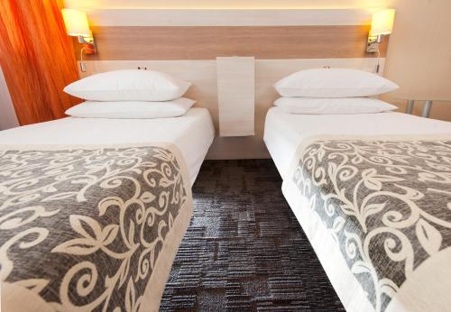 a hotel room with two beds and two lamps at Comfort by Trio in Białystok