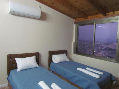 2 Betten in einem Zimmer mit Fenster in der Unterkunft Royal Guest House in Nazareth