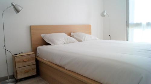 une chambre avec un lit blanc avec une tête de lit en bois dans l'établissement Appart Hôtel Lille Baudoin, à Lille