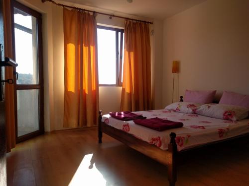 a bedroom with a bed and two windows at Villa Visoka in Balchik