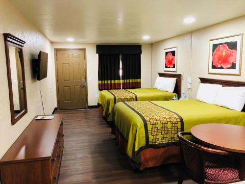 Habitación de hotel con 2 camas y mesa en Deluxe Inn - Sarasota, en Sarasota