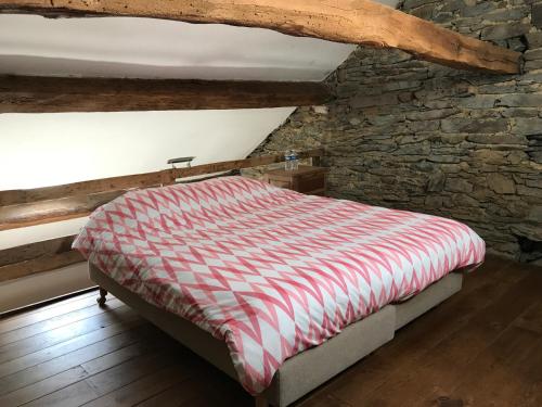 a bed in a room with a stone wall at Ferme du Grand Frêne in Naomé