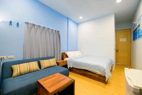 a living room with a couch and a bed at 夏海民宿 in Magong