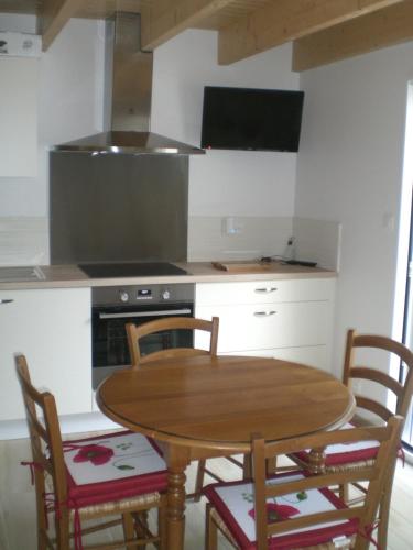 une cuisine avec une table et des chaises en bois dans l'établissement La Saligotiere, à Longeville-sur-Mer