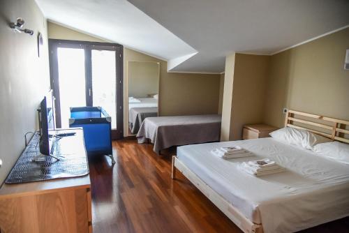una camera d'albergo con 2 letti e una scrivania con un computer di Attic Aries a Montesilvano