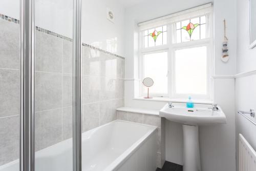 ein weißes Bad mit einer Badewanne, einem Waschbecken und einer Dusche in der Unterkunft City Apartments - 4 Heworth Village - 3 bed house in York
