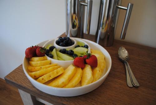 a bowl of fruit with strawberries and blueberries on a table at Stone Lodge in Holt