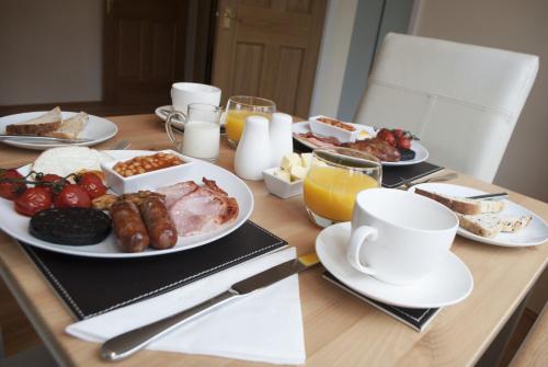 a table topped with plates of breakfast foods and orange juice at Stone Lodge in Holt