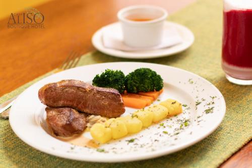 a plate of meat and vegetables with a cup of coffee at Casa Aliso Hotel Boutique in Quito