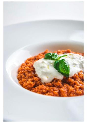 a white bowl of chili with sour cream and basil at TH Assisi - Hotel Cenacolo in Assisi