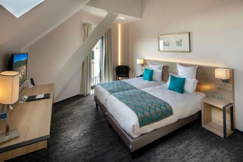 a hotel room with a large bed with blue pillows at Best Western Plus Hotel & SPA Le Schoenenbourg in Riquewihr