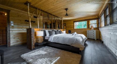 um quarto com uma cama num chalé de madeira em Chalet TAO par Les Chalets Spa Canada em La Malbaie
