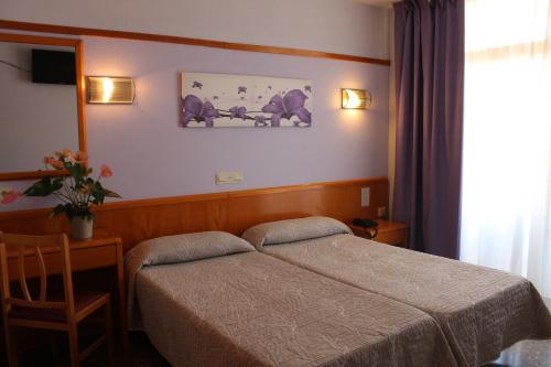 1 dormitorio con cama, mesa y ventana en Hotel Esplendid, en Blanes