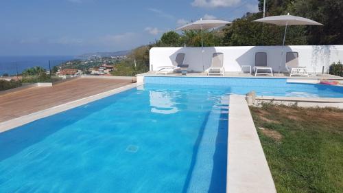 a blue swimming pool with chairs and an umbrella at Appartamenti Borgo Panoramico n.1 in Tropea