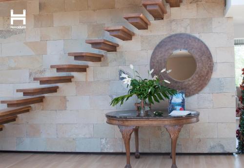a stone wall with a circular mirror and a table at Herradura Hotel Suites in Neuquén