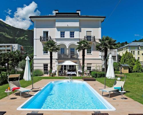 ein Haus mit einem Pool vor einem Gebäude in der Unterkunft Garni Villa Tyrol - Adults Only in Meran