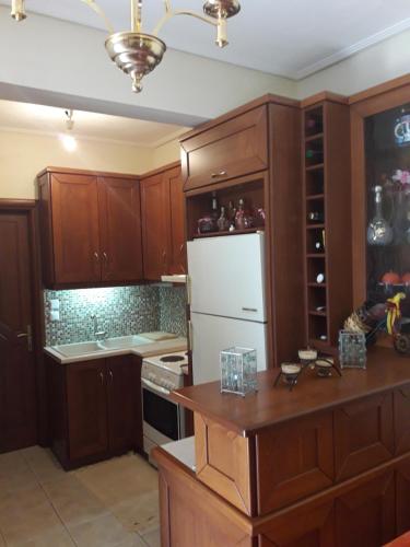 a kitchen with wooden cabinets and a white refrigerator at Poly's Sea Side House in Koropi