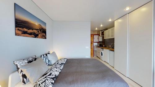 a white room with a bed and a kitchen at Cosy 0cean View Studio 1 in Icod de los Vinos