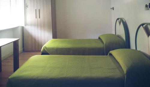 2 letti verdi in una camera con tavolo di Cà della Roggia a Rovereto