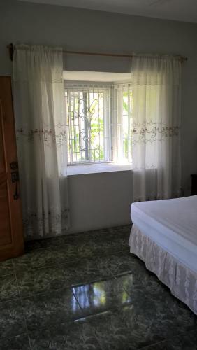 a bedroom with a bed and a window at Fairy Hill Palms in Port Antonio