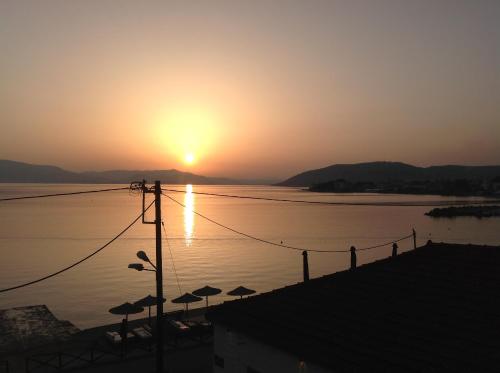 a sunset over a body of water with umbrellas at FILIPPOS-Spectacular area,,,,panoramic,-sea- view- apartments-42m, just call on the photo number, for price,vacancy etc,,-next to Vallis hotel,, 15meters from seaside!!! in Agria