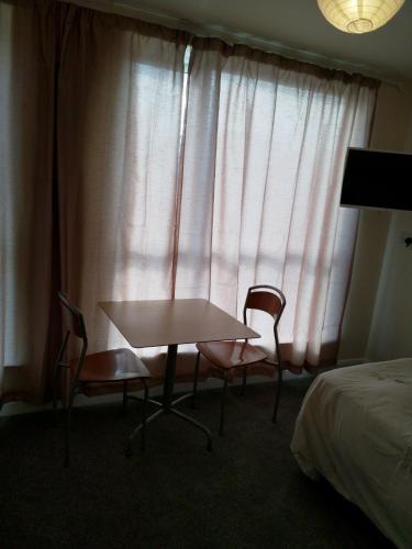 a table and chairs in a hotel room with a window at Denny Guests House / Green Lane in Liverpool