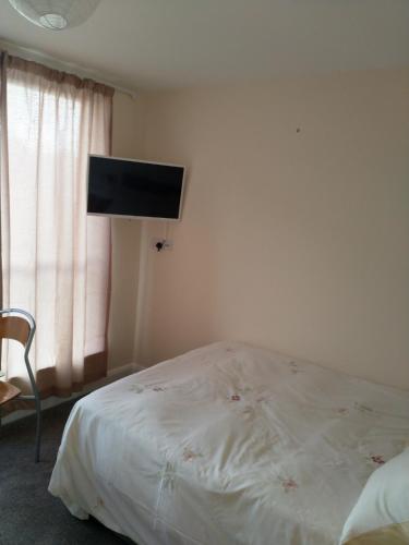 a bedroom with a bed and a flat screen tv at Denny Guests House / Green Lane in Liverpool