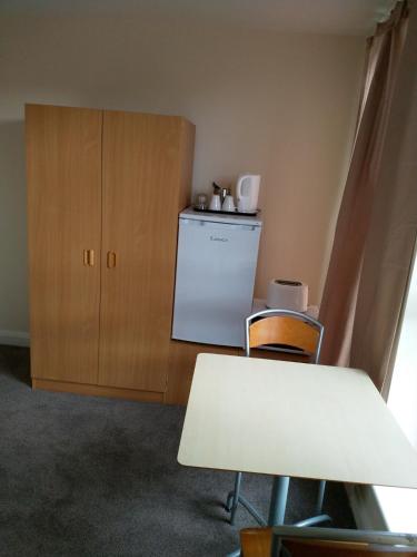 a kitchen with a refrigerator and a table and chairs at Denny Guests House / Green Lane in Liverpool