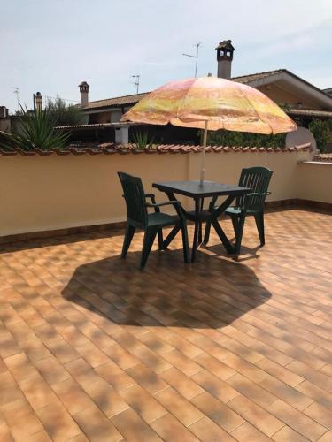 a table with two chairs and an umbrella on a patio at Mirella's House ViaVerona in Ardea