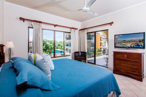 a bedroom with a blue bed and a television at Stay in Tamarindo Condominiums in Tamarindo