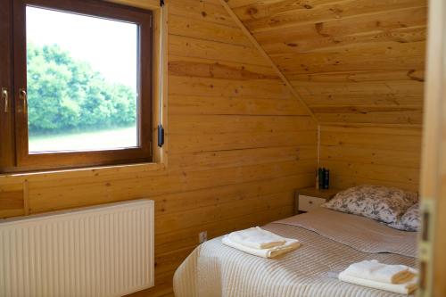 a bedroom with a bed in a wooden room with a window at Domki Luksusowe Eskada in Ustronie Morskie