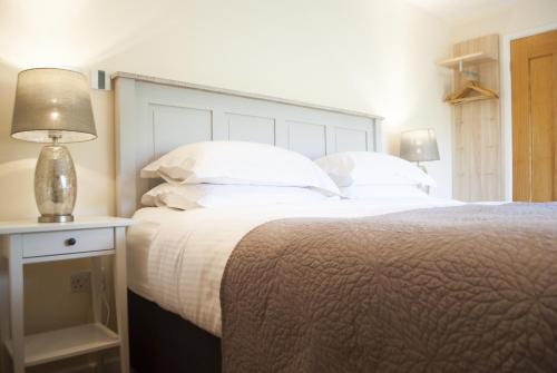 una camera da letto con un grande letto con lenzuola e cuscini bianchi di Stone Lodge a Holt