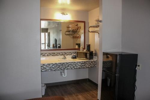 a bathroom with a sink and a mirror and a refrigerator at Rayburn Inn in Brookeland