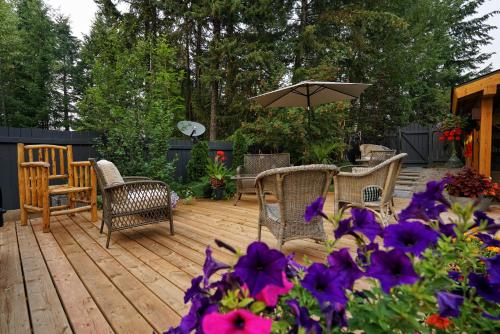 a wooden deck with chairs and an umbrella and purple flowers at Deer Ridge B&B in Golden