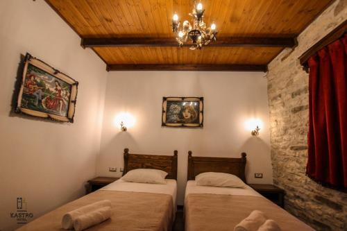 a bedroom with two beds and a chandelier at Hotel Kastro in Gjirokastër