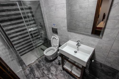 a bathroom with a toilet and a sink and a shower at Hotel Kastro in Gjirokastër