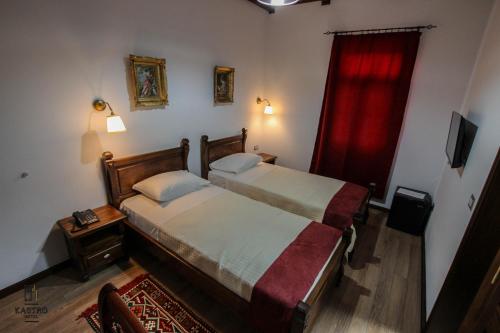a bedroom with two beds and a red curtain at Hotel Kastro in Gjirokastër
