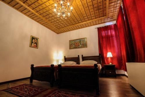 a bedroom with a bed with red curtains and a chandelier at Hotel Kastro in Gjirokastër