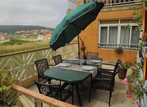 a table and chairs with an umbrella on a balcony at CASA VACACIONAL NIÑONS-PONTECESO in Ponteceso