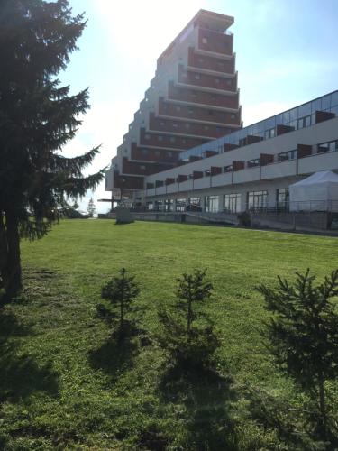 a large building with two trees in a field at Apartman Panorama 213, Štúdio Comfort in Štrbské Pleso