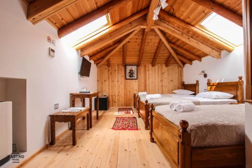 een slaapkamer met 3 bedden in een kamer met houten plafonds bij Hotel Kastro in Gjirokastër