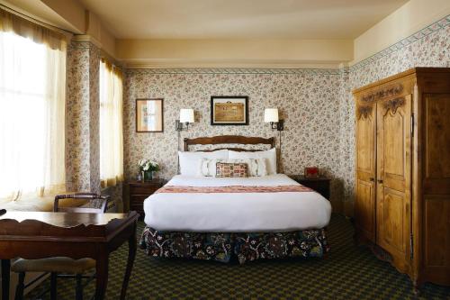 a hotel room with a bed and a desk and a bed sidx sidx at Petite Auberge in San Francisco