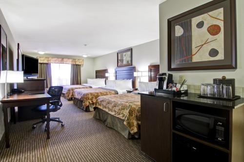 a hotel room with two beds and a desk at Canalta Hotel Weyburn in Weyburn